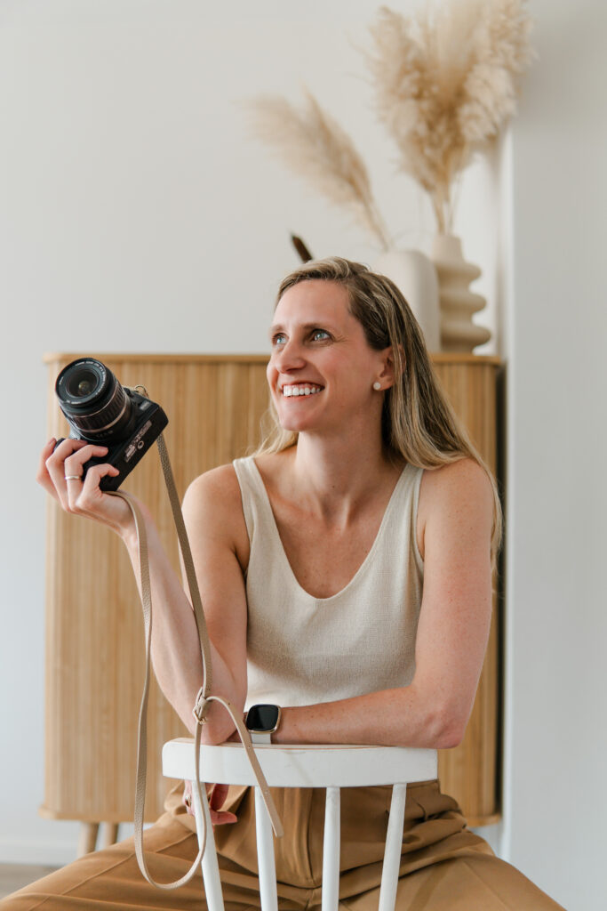 Esther zittend op een stoel met een camera in haar hand.