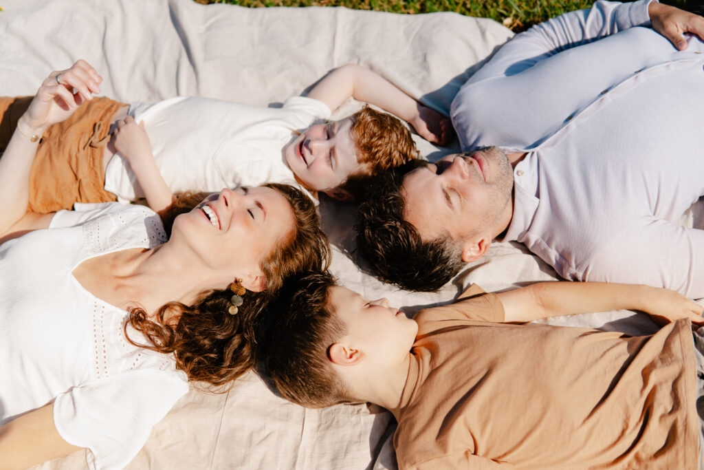 Gezin ligt op een kleed met hun hoofden bij elkaar.